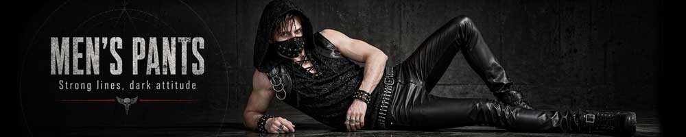 Male model in black goth strap pants with chains, cargo pockets, and D?ring details, standing against an industrial backdrop.