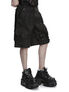 Black cargo shorts worn with black boots, side view on a white background