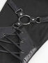 Close-up of black harness pants featuring straps and metal rings for a stylish design.