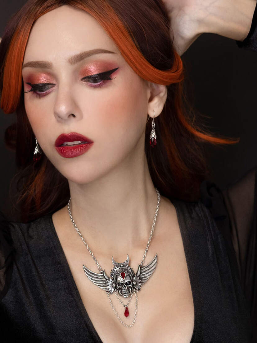 Immortal Ayesha Winged Skull Necklace A woman wearing the Immortal Ayesha Winged Skull Necklace with red lipstick and dramatic eye makeup.