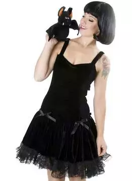 Front view of a woman in a black velvet dress with lace trim and shoulder straps, holding a plush black cat