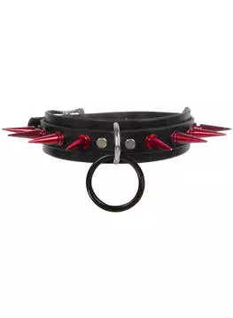 Close-up of a black choker with red spikes, black O-ring in the center, and metal rivets